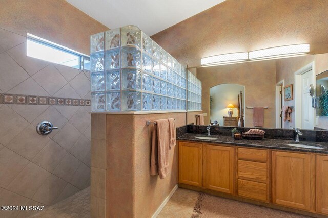 full bathroom featuring a sink, a walk in shower, tile patterned flooring, and double vanity