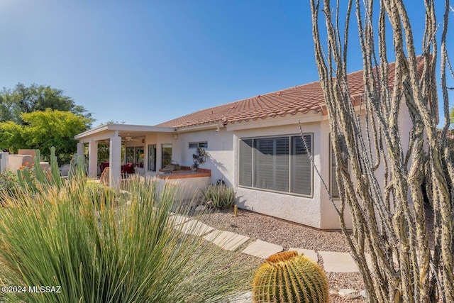 rear view of house featuring a patio, stucco siding, area for grilling, a ceiling fan, and a tile roof