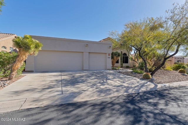 pueblo-style house with an attached garage, stucco siding, and concrete driveway