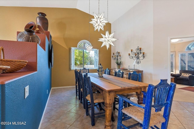 tiled dining room with high vaulted ceiling, plenty of natural light, and baseboards