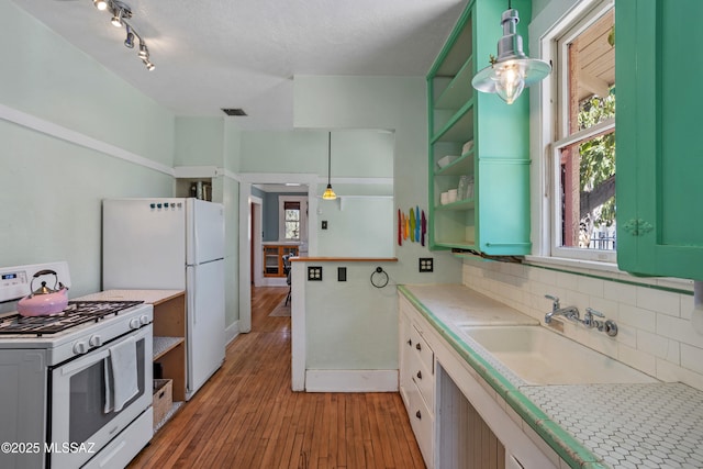 kitchen featuring tasteful backsplash, open shelves, a sink, light wood finished floors, and white appliances