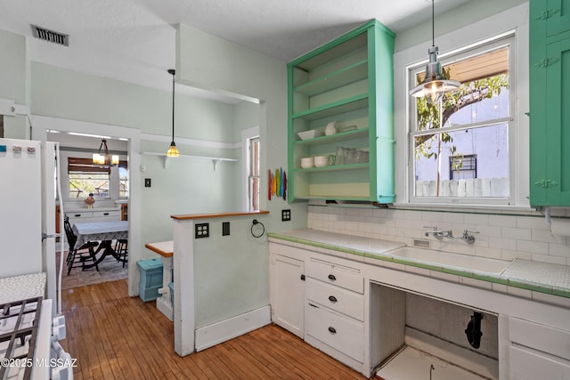 interior space featuring plenty of natural light, backsplash, visible vents, a sink, and light wood-style flooring