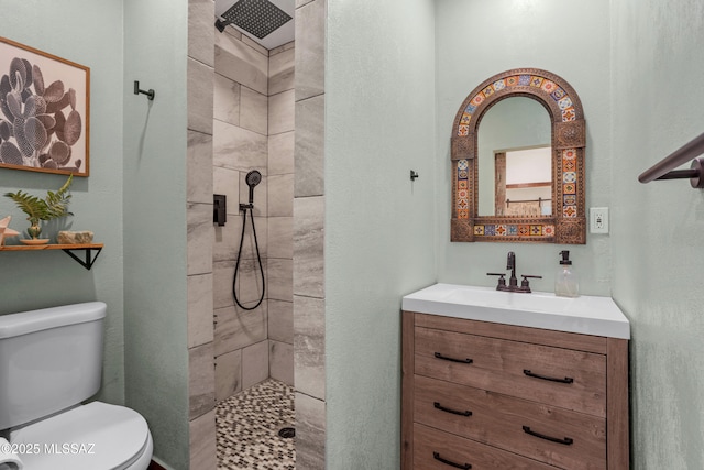 full bath with toilet, a tile shower, and vanity