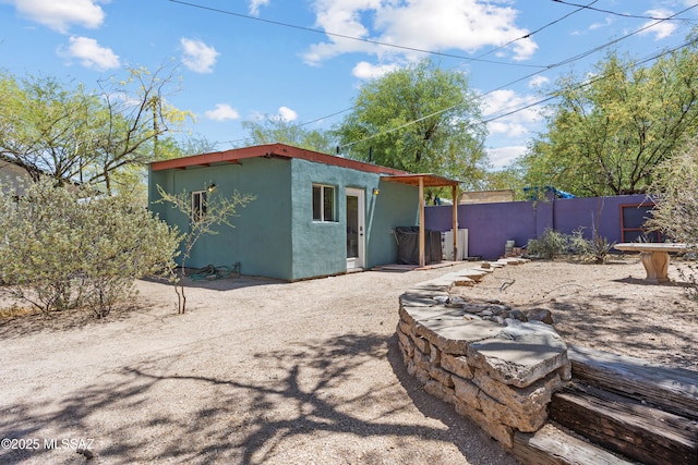 exterior space with fence, an outdoor structure, and stucco siding