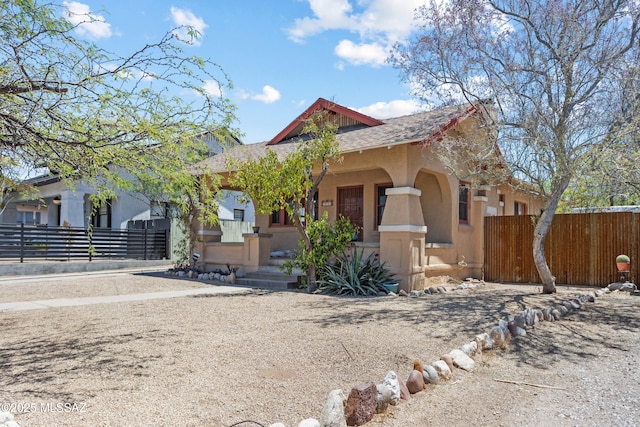 view of front of property with stucco siding, covered porch, and fence