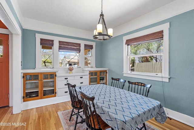 dining area featuring baseboards, light wood finished floors, and a notable chandelier