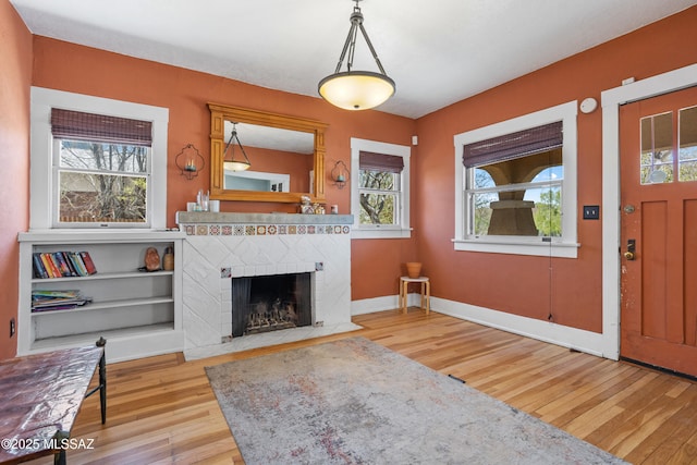 living room featuring a brick fireplace, a healthy amount of sunlight, and hardwood / wood-style floors