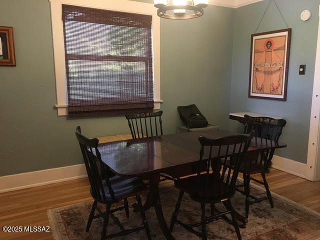 dining area featuring baseboards, a chandelier, and wood finished floors