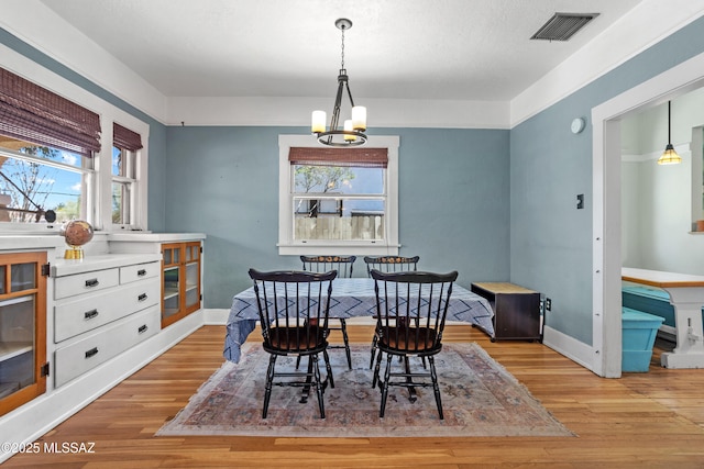 dining area with visible vents, a chandelier, wood finished floors, and a wealth of natural light