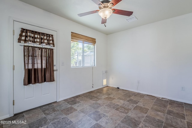 interior space with stone finish floor, baseboards, ceiling fan, and visible vents