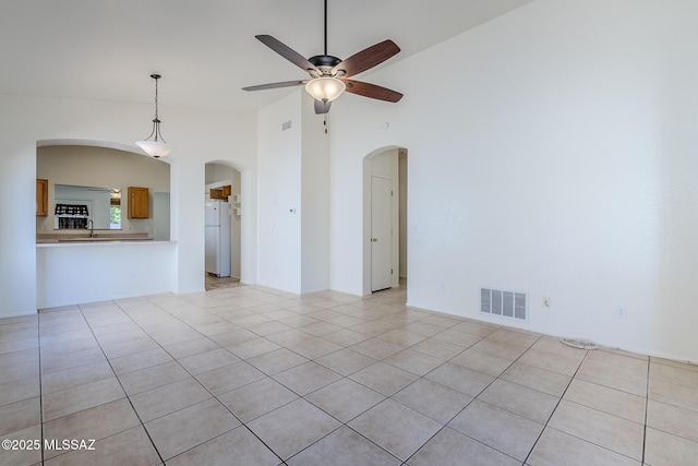 unfurnished living room with a ceiling fan, arched walkways, visible vents, and light tile patterned floors