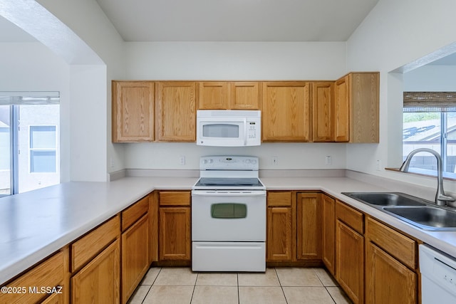 kitchen with a sink, light countertops, white appliances, and light tile patterned flooring
