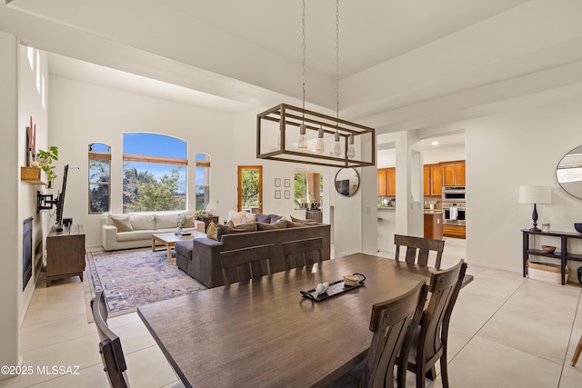 dining room featuring light tile patterned floors, baseboards, and a high ceiling