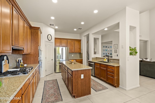 kitchen with a sink, stainless steel appliances, decorative backsplash, a kitchen island, and visible vents
