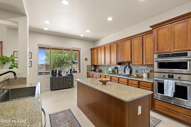 kitchen with light tile patterned floors, appliances with stainless steel finishes, a sink, and a center island