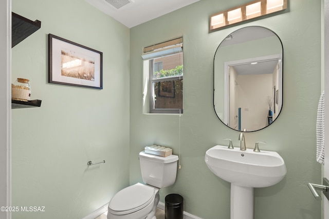 half bath with a sink, baseboards, toilet, and visible vents