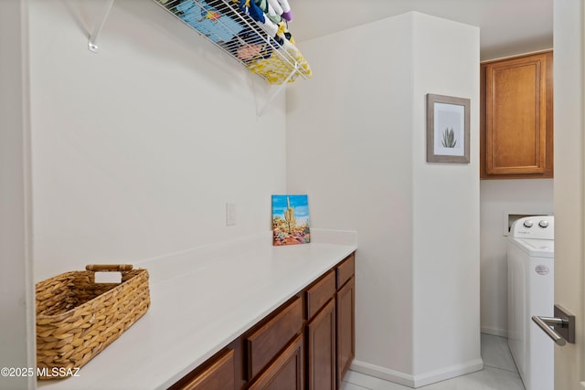 laundry area with baseboards, washer / dryer, cabinet space, and light tile patterned floors