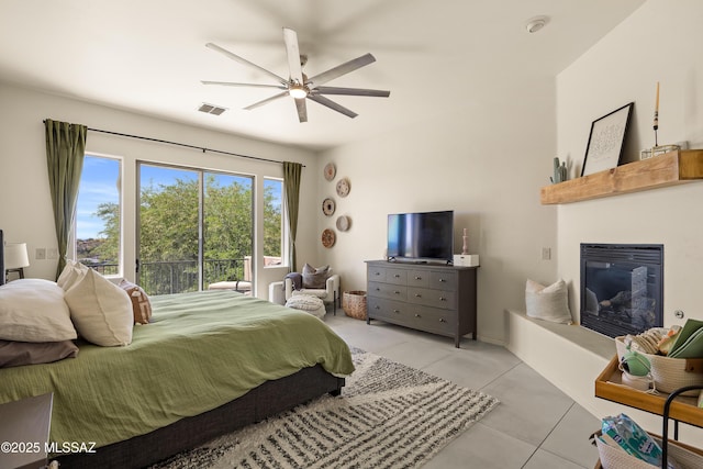 bedroom featuring ceiling fan, access to exterior, visible vents, light tile patterned floors, and a glass covered fireplace