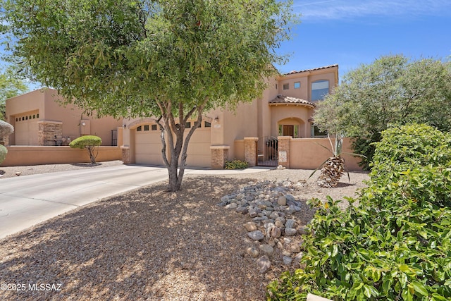 view of front facade featuring fence private yard, stucco siding, a gate, concrete driveway, and a tile roof