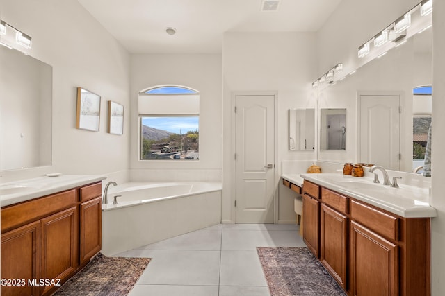 bathroom with a sink, tile patterned flooring, two vanities, visible vents, and a bath