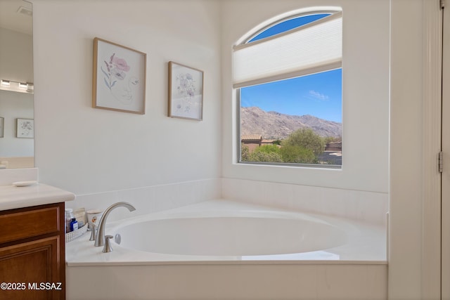 full bath featuring vanity, plenty of natural light, a mountain view, and a bath