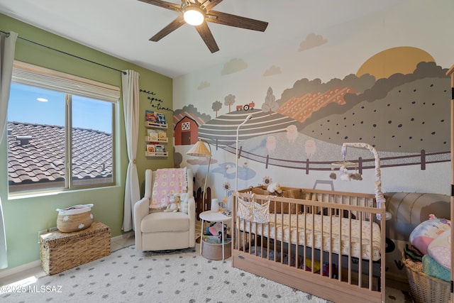 carpeted bedroom featuring a nursery area, baseboards, and a ceiling fan