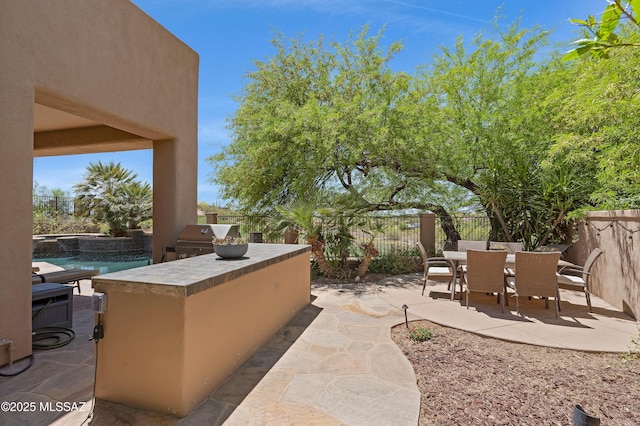 view of patio / terrace featuring a fenced backyard, outdoor dining space, area for grilling, and an outdoor kitchen