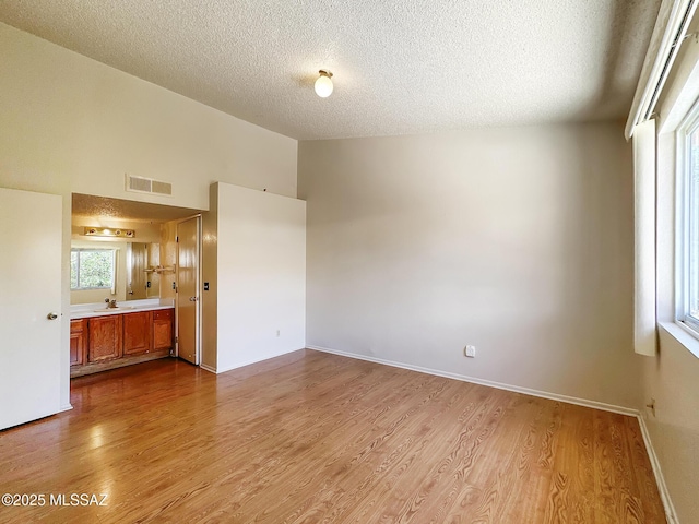 10084 E Bryonwood Ln, Tucson, AZ 85730 - empty room with a textured ceiling, wood finished floors, and vaulted ceiling