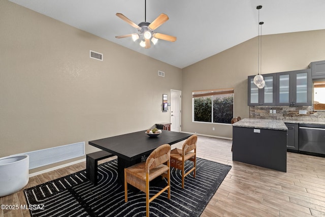 dining room with visible vents, light wood-style floors, ceiling fan, and high vaulted ceiling