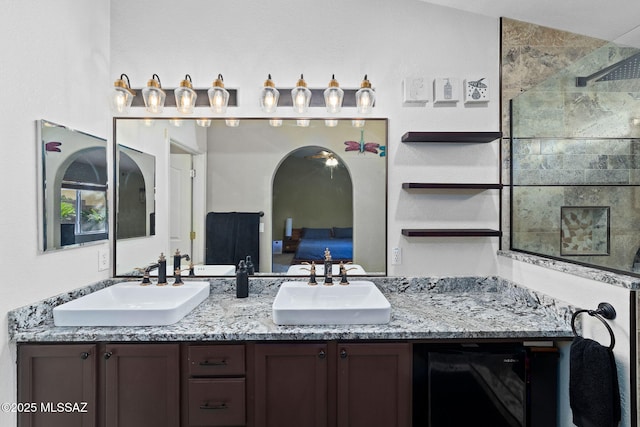 full bathroom featuring double vanity, a tile shower, a sink, and ensuite bath