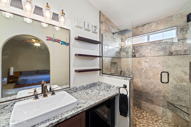 ensuite bathroom with vanity, ensuite bathroom, beverage cooler, tiled shower, and a ceiling fan