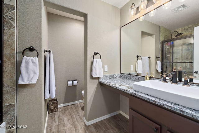full bathroom featuring visible vents, wood finished floors, toilet, baseboards, and tiled shower