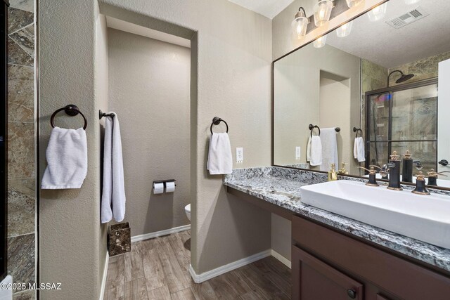 9696 E Paseo, San Rosendo, Tucson, AZ 85747 - full bathroom featuring visible vents, wood finished floors, toilet, baseboards, and tiled shower
