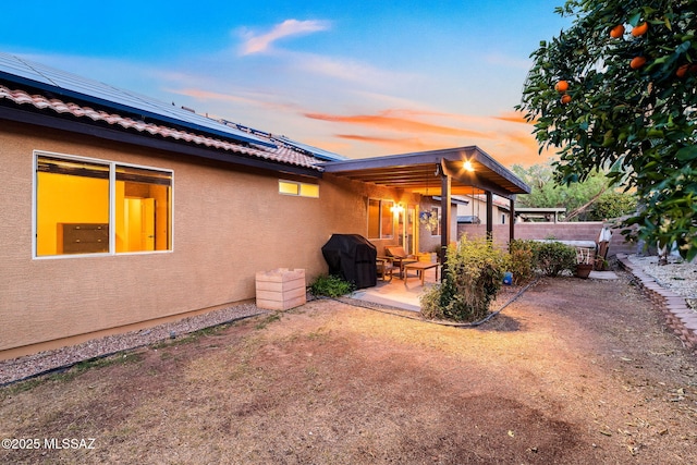 rear view of property with fence, a patio, stucco siding, and solar panels