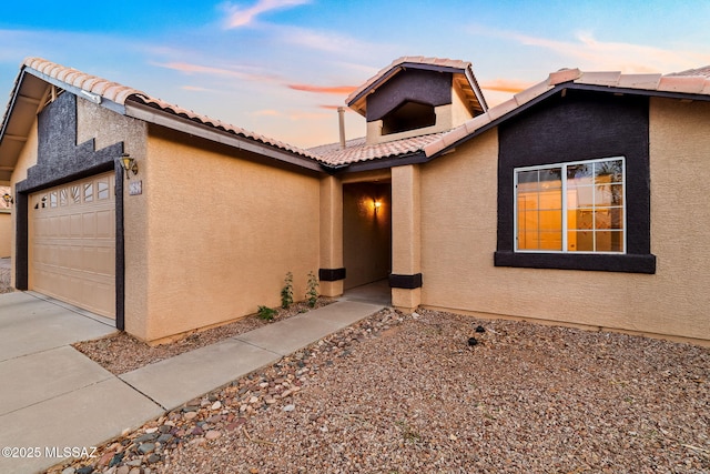 view of front of home featuring a tiled roof, a garage, concrete driveway, and stucco siding