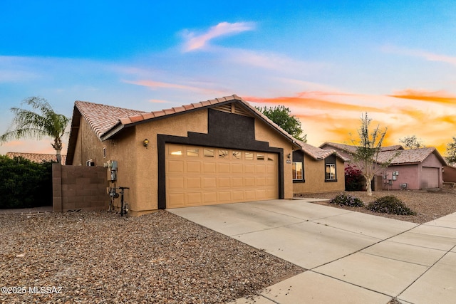 view of front of home with a garage, stucco siding, driveway, and a tiled roof