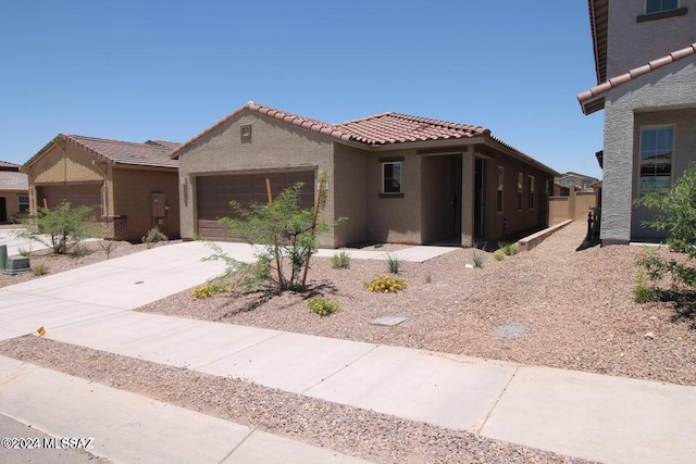 view of front of home with an attached garage, driveway, a tile roof, and stucco siding