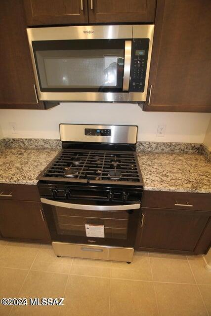 kitchen with dark brown cabinets, appliances with stainless steel finishes, and light tile patterned floors