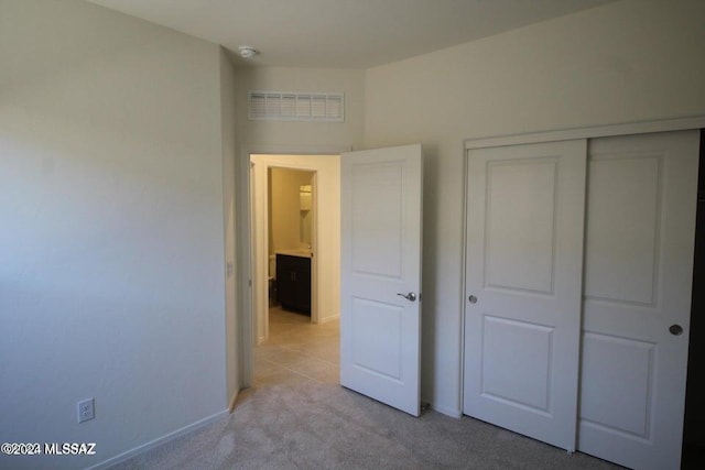 unfurnished bedroom with baseboards, light carpet, a closet, and visible vents
