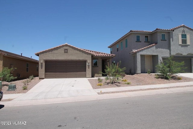mediterranean / spanish-style home featuring a tiled roof, a garage, driveway, and stucco siding
