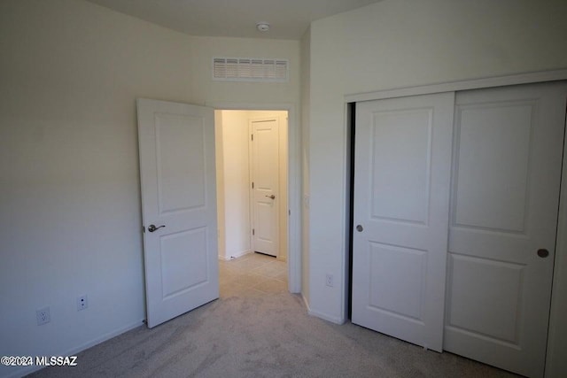 unfurnished bedroom with baseboards, light carpet, a closet, and visible vents