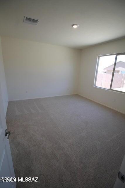 carpeted spare room featuring baseboards and visible vents