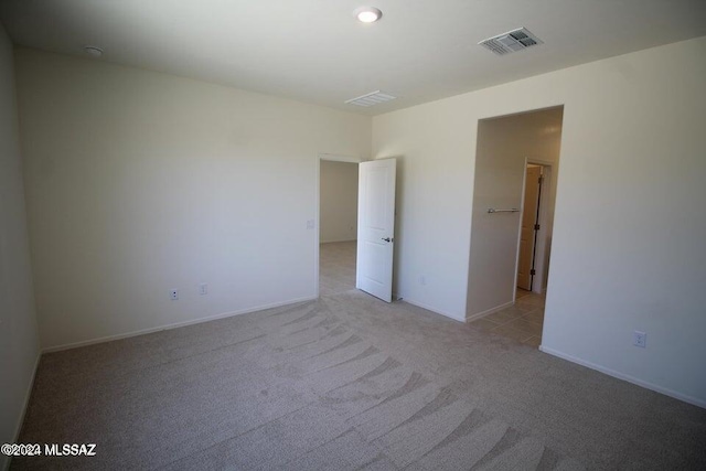 empty room featuring baseboards, visible vents, and light carpet