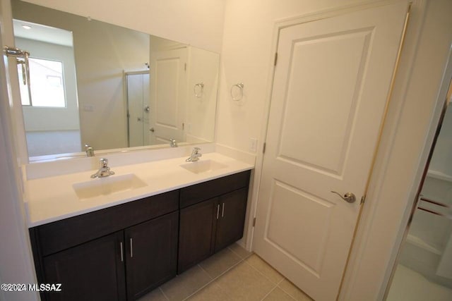 bathroom with a sink, tile patterned flooring, a shower stall, and double vanity