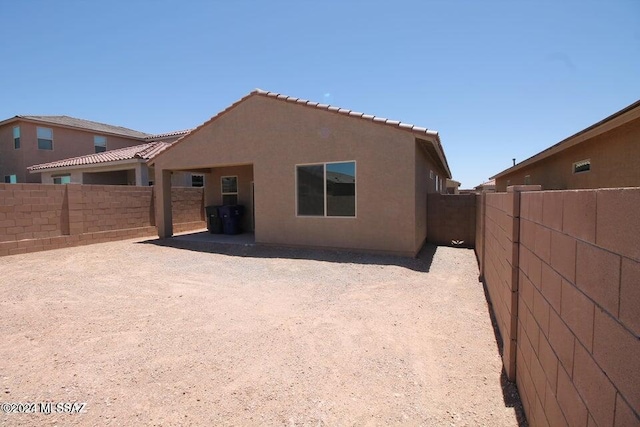 rear view of house with a fenced backyard, stucco siding, and a tiled roof