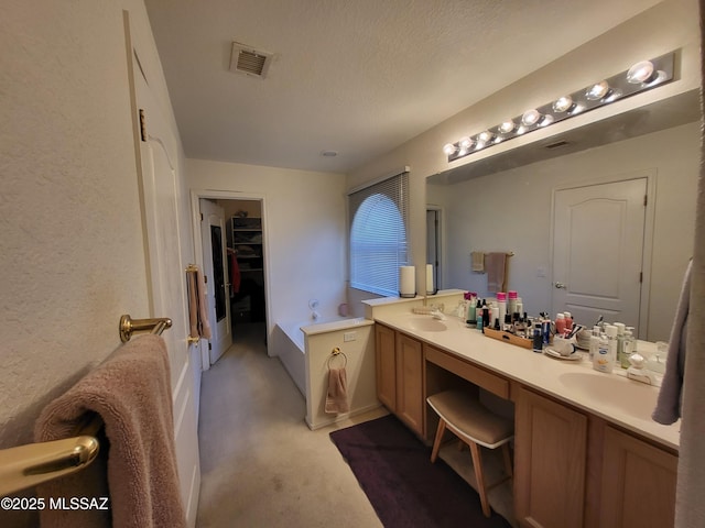 10161 E Queensgate Way, Tucson, AZ 85748 - bathroom featuring double vanity, a walk in closet, a textured ceiling, visible vents, and a sink