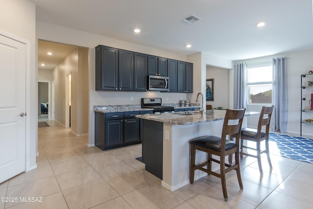 kitchen with visible vents, a kitchen breakfast bar, light stone counters, a sink, and stainless steel appliances