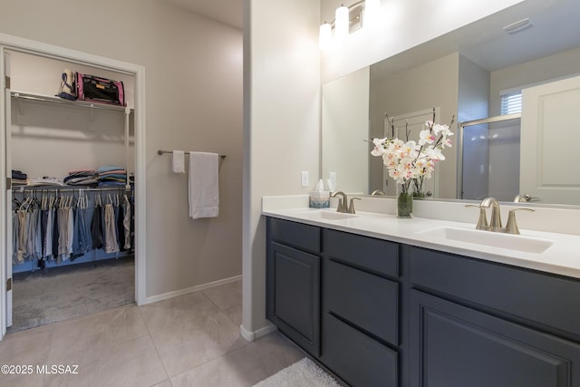 bathroom featuring double vanity, a spacious closet, and a sink