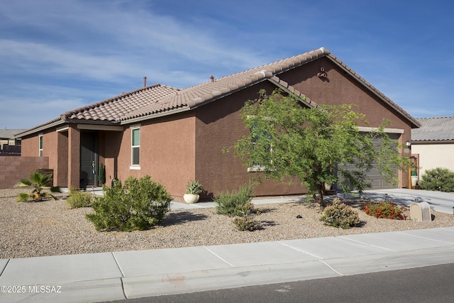 view of side of property with fence, a tiled roof, an attached garage, and stucco siding