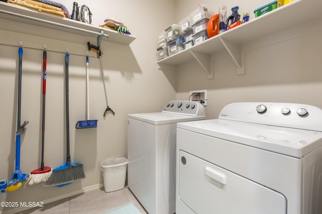 laundry room featuring laundry area, baseboards, light tile patterned floors, and washing machine and dryer